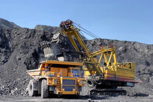 The picture shows a dredge loading a truck with coal in a coal mine